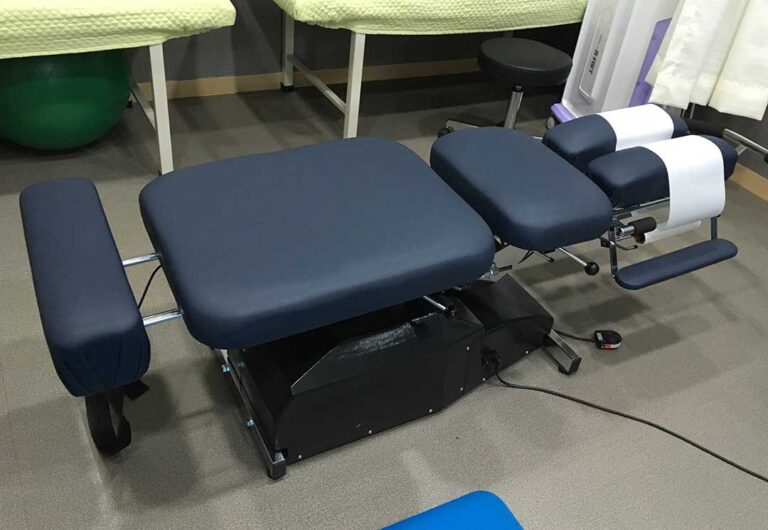 Patient discusses back pain with a chiropractor during an examination in a bright treatment room.