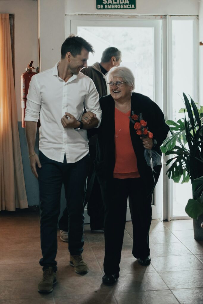 Older adult performing a gentle mobility exercise beside a stable chair in a bright home setting.